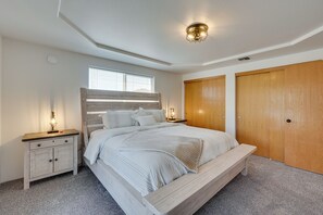 A bedroom with a large bed, wooden headboard, two bedside tables with lamps, and a wardrobe. - Charming Rogue Valley Home in Central Point! (Central Point)