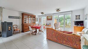 Ein geräumiger Wohnbereich mit Esstisch, Stühlen, einer Couch und einem Fernseher.