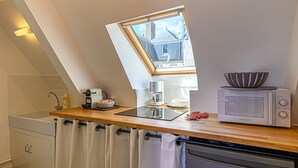 A kitchen with a skylight, a coffee maker, a bowl, and a microwave.