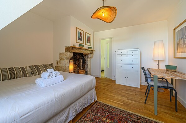 Une chambre à coucher avec un lit, une cheminée, un bureau avec une lampe et une chaise.