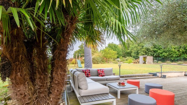 Eine Terrasse mit einer Couch, Hocker und einem Tisch.