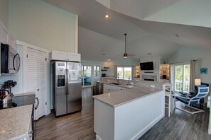 A modern kitchen with a large island, built-in appliances, and a dining area with a view. - Close to beach, Remodeled! Flex Stays! Dogs OK! Pool, C7821 (Corolla)
