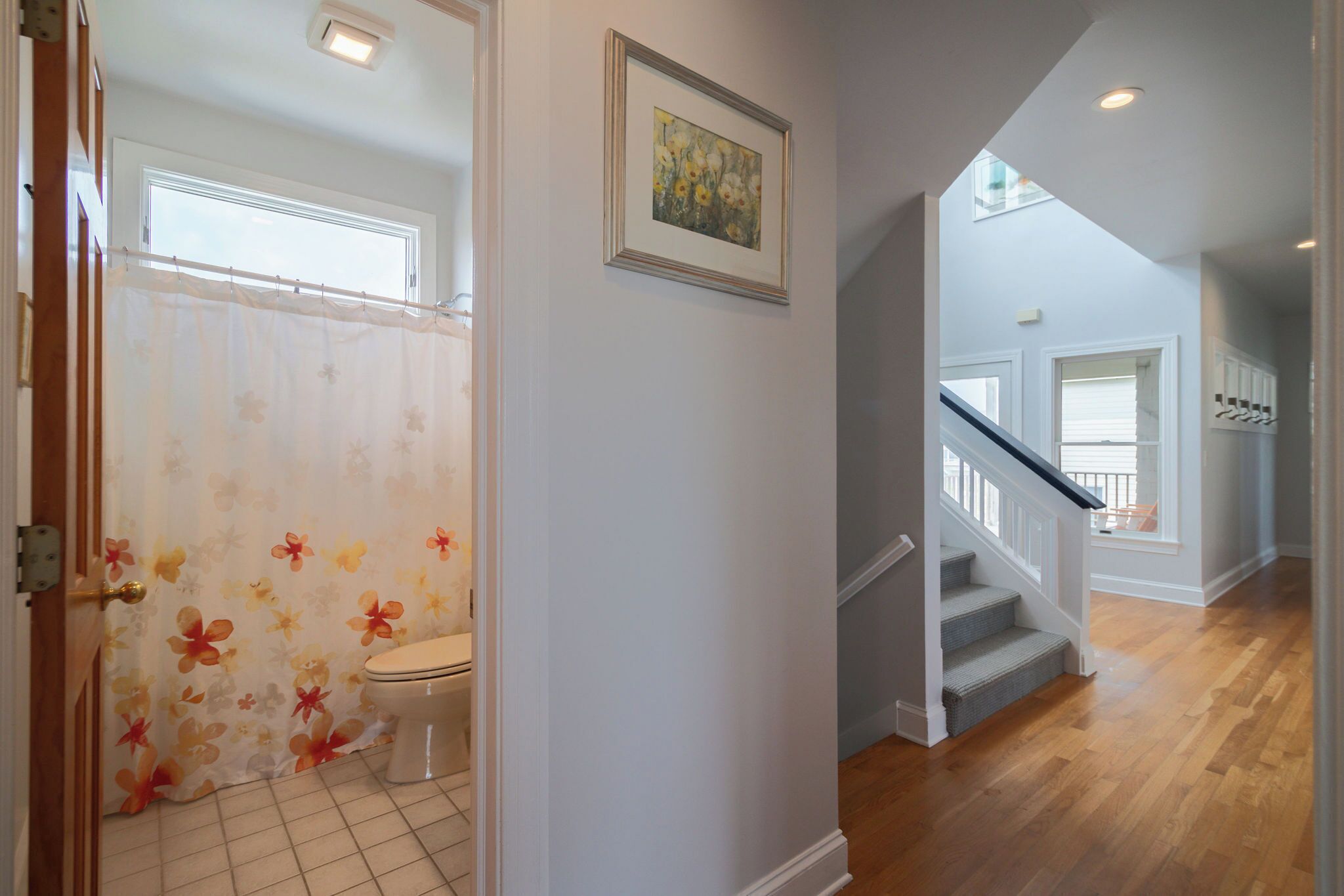 A bathroom with a toilet, shower curtain, and a framed painting on the wall.