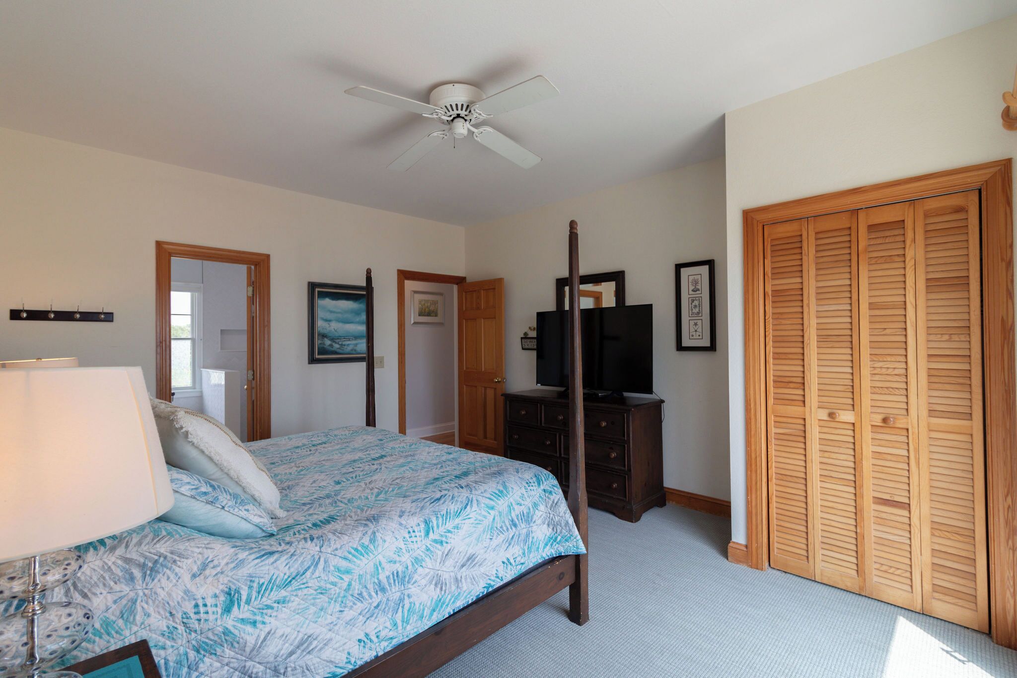 Une chambre à coucher comprenant un lit, un ventilateur de plafond, une télévision, une commode et un placard.