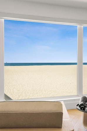 A room with a large window overlooking a beach.