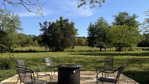 Un patio al aire libre con suelo de piedra, un brasero y sillas de metal.