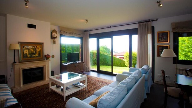 Una sala de estar con chimenea, sofá, mesa de centro y televisor.