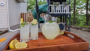Un plateau en bois avec deux verres de limonade et une carafe, accompagné de rondelles de citron.