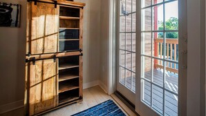Una habitación con un armario de madera con varios cajones, un ventanal con vista a una terraza, y una alfombra azul en el suelo.
