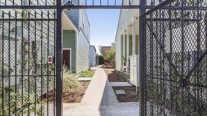 A gated pathway leading to a row of light green buildings with a clear sky above. - Cute 1bed walk to French Q & Bourbon St (New Orleans)