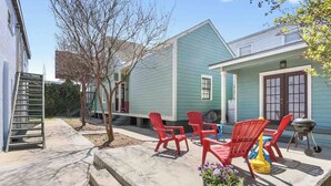 A house with a covered patio area featuring red plastic chairs and a barbecue grill. - Cute 1bed walk to French Q & Bourbon St (New Orleans)