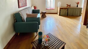 A spacious living room with a wooden floor, a green sofa, a coffee table with decorative items, and a window with a view. - Syunning, spacious & calm. 60m squared in the heart of Avignon  (Avignon)