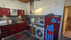 A compact kitchen with red cabinets, a washing machine, a microwave, and a refrigerator. - Duplex 6/8 Pers 90 m² Le Bez Serre Chevalier 1400 (La Salle-les-Alpes)