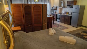Een hotelkamer met een bed, een houten scheidingswand, een kitchenette en een kleine tafel.