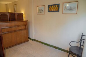 Ein Zimmer mit einem Holzschrank, einem Stuhl und drei gerahmten Kunstwerken an der Wand.