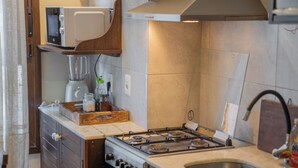 Een kleine keuken met een gasfornuis, een magnetron en een ingebouwde oven.