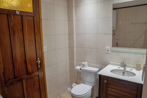 Ein Badezimmer mit Holztür, Toilette, Waschbecken und Spiegel.