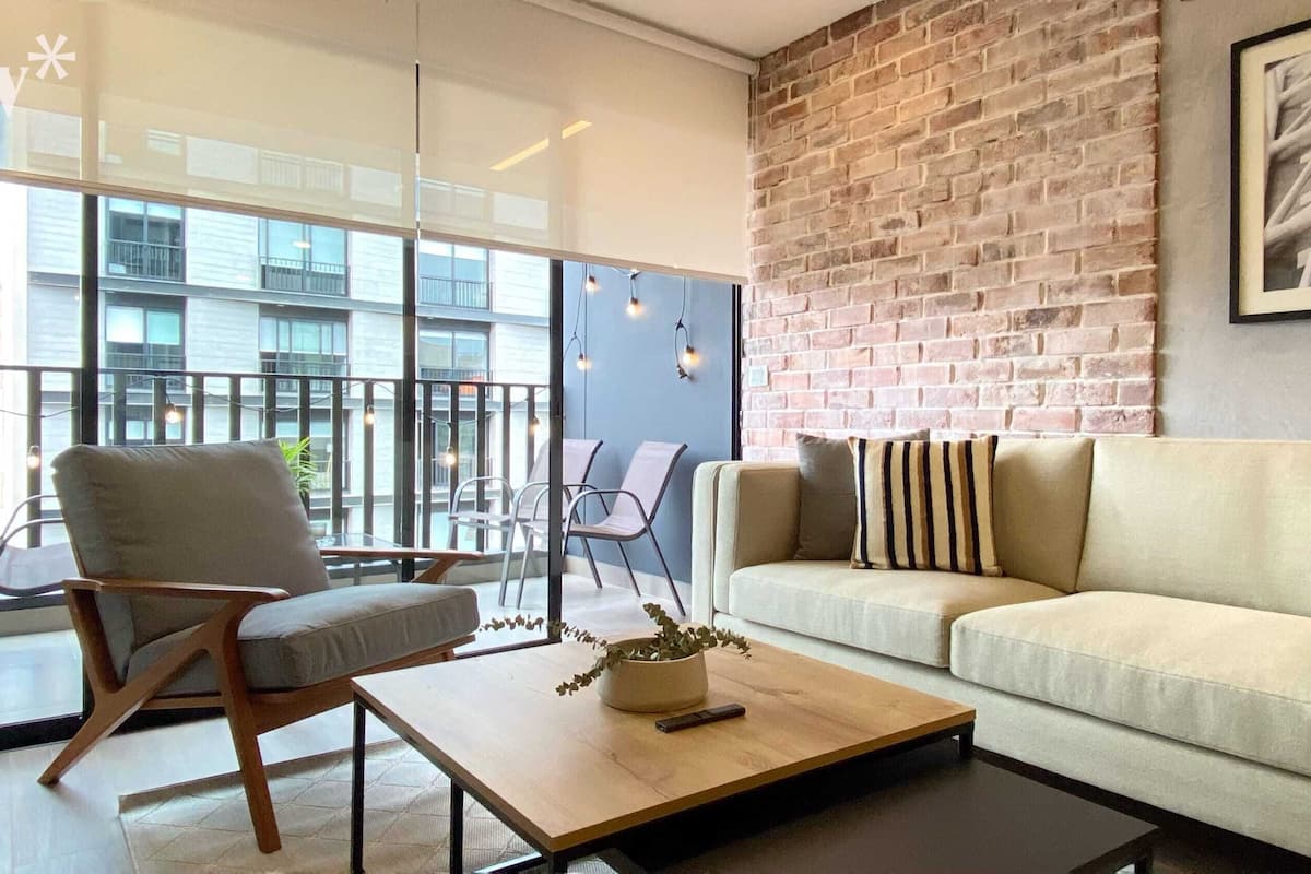 A modern living room with a brick wall, a sofa, a chair, and a coffee table.