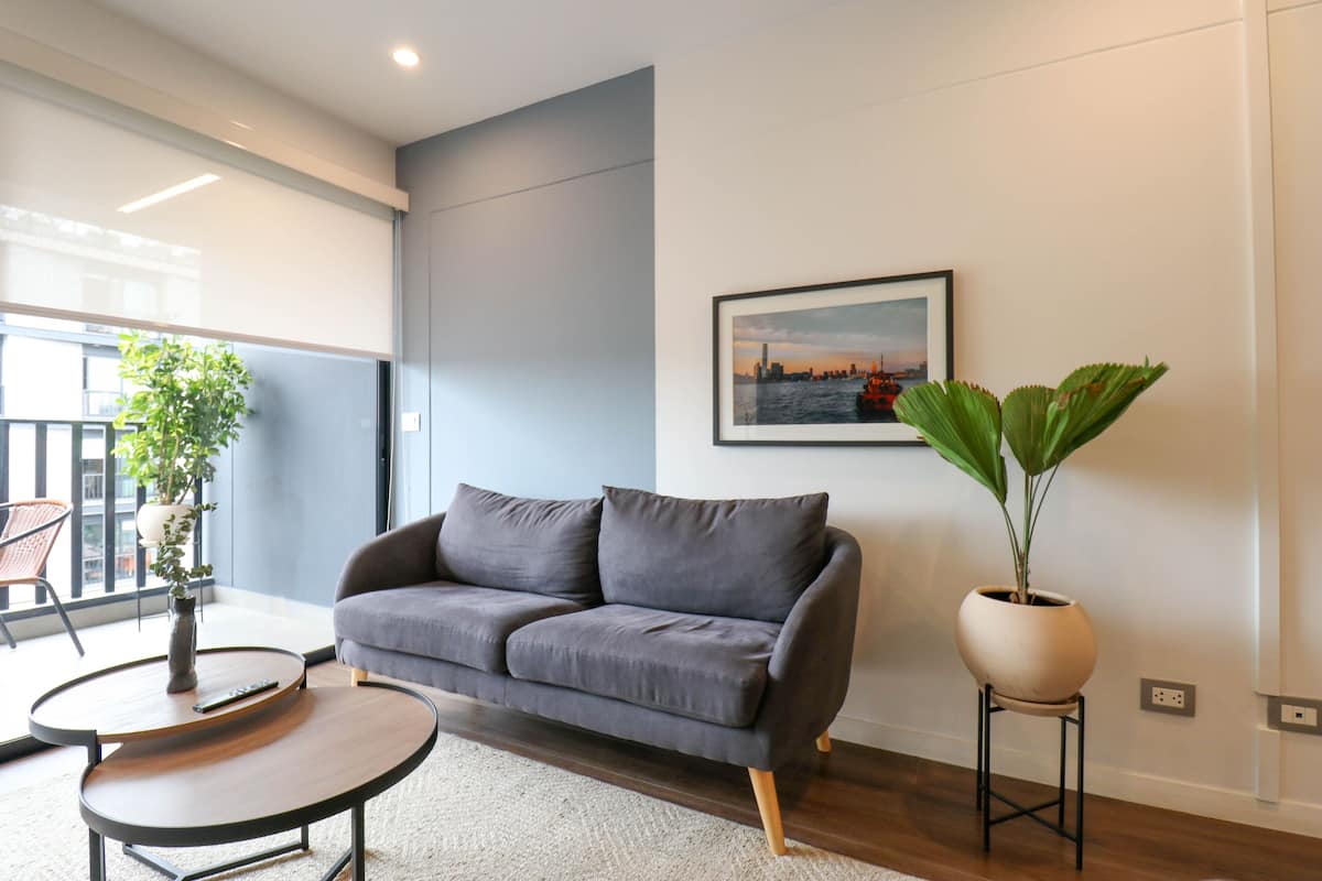 A modern living room with a grey sofa, a round coffee table, and a large potted plant.