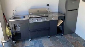 Eine kompakte Küchenzeile mit Spüle, Herd und Kühlschrank, inklusive Backofen und kleiner Mülltonne.