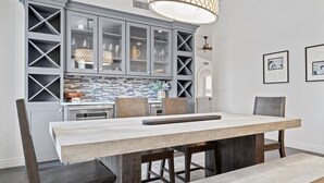 Een moderne keuken met een groot eiland, grijze keukenkastjes en een hangende lamp.