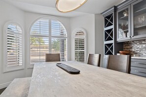 Enjoy meals together at the spacious dining table, surrounded by modern cabinetry and a stylish backsplash.