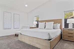 Relax in a serene bedroom with a large bed, nightstand, and artwork.