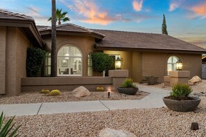Stucco exterior and tiled roof characterize this charming home, featuring a central entrance and arched windows.