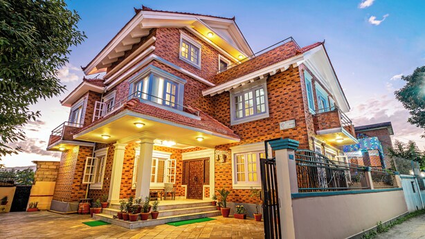 A two-story house with a brick exterior, a balcony, and a gated entrance. - Panas UK BNB (Kathmandu)