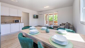Une cuisine moderne avec des meubles blancs, un four à micro-ondes et un coin repas doté d’une table en bois, mise pour quatre personnes.
