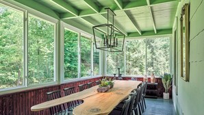 Un lungo tavolo di legno con sedie in una stanza con ampie finestre e soffitto verde.