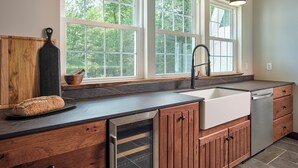 Cucina con una grande finestra, un lavandino e pensili in legno.
