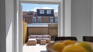 A view through an open door into a room with a sofa set and a dining table with a bowl of fruit. - 3BR Chic House withParking Sleeps 8, Big Groups! (Portsmouth)