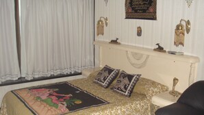 Un dormitorio con cama, mesita de noche, silla y adornos en la pared.
