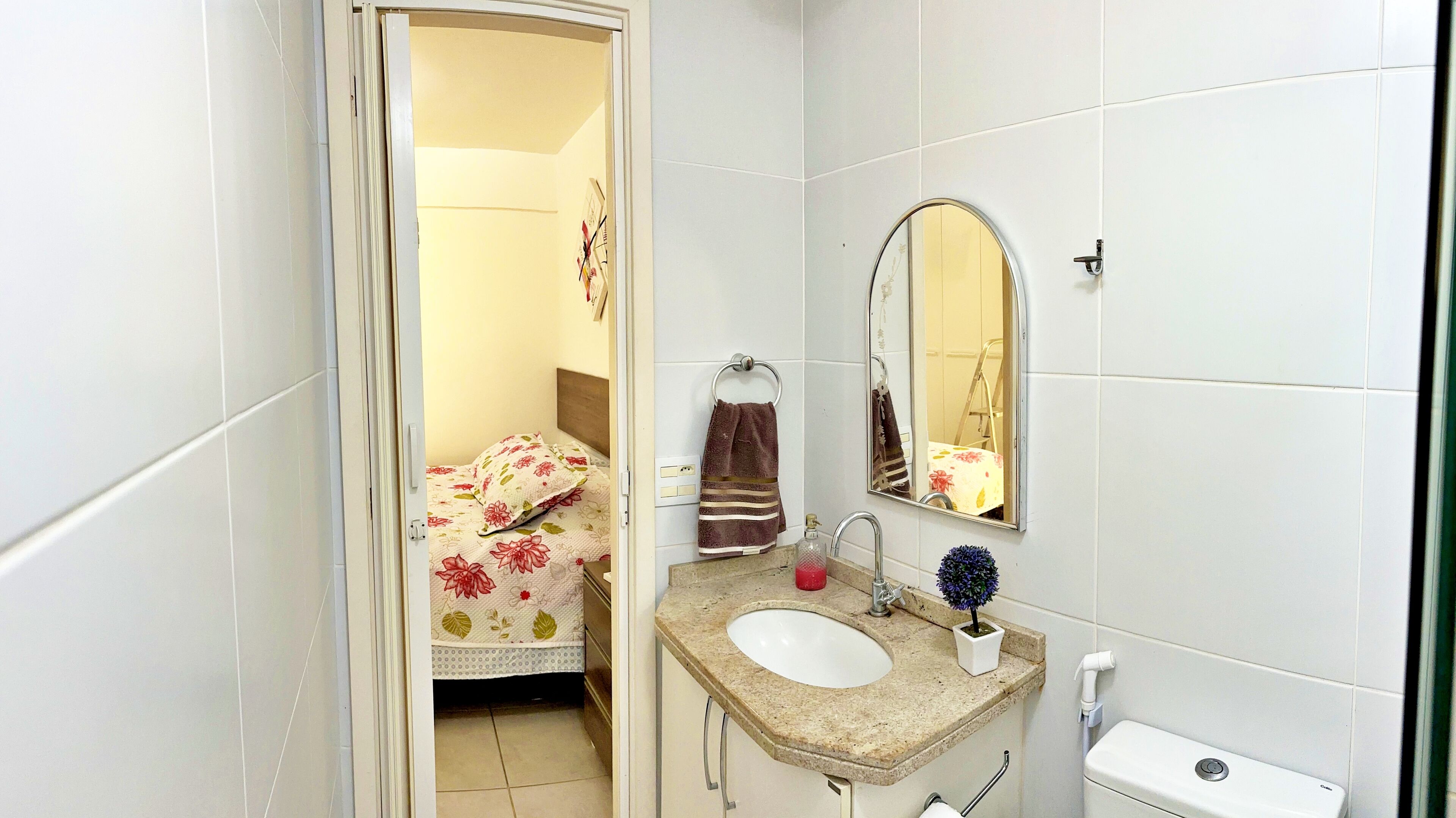 A small, clean bathroom with a sink, mirror, and toilet.