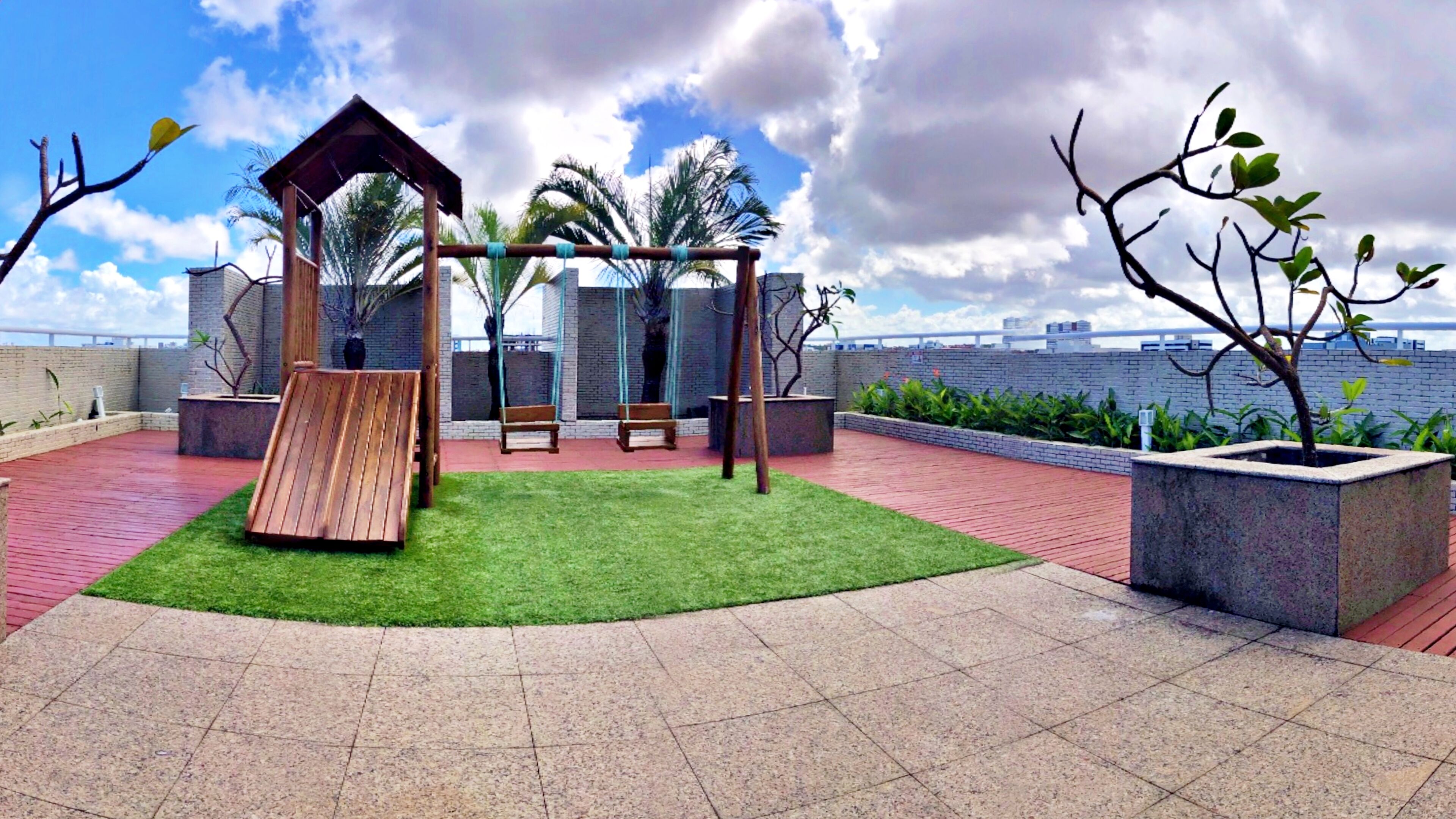 A rooftop garden with a wooden swing set, benches, and a small gazebo.