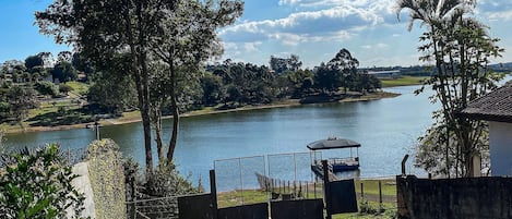 Vista de un lago con un pabellón, una zona vallada y un camino que lleva al agua.