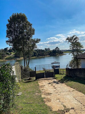 Vista para o lago com um gazebo, área cercada e um caminho que leva à água.