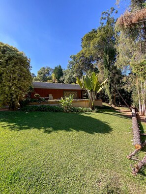 A well-maintained garden with a variety of plants and a building in the background. - Chácara Espetacular em Ibiúna (Ibiuna)