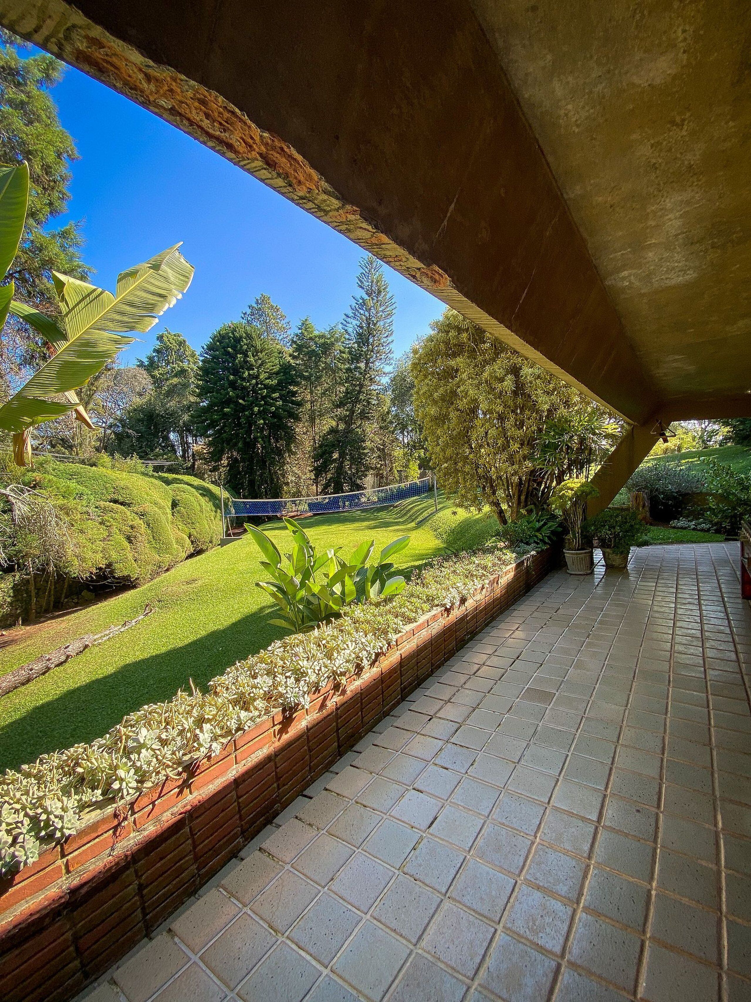 A covered patio area with a view of a well-maintained garden and a sports field.