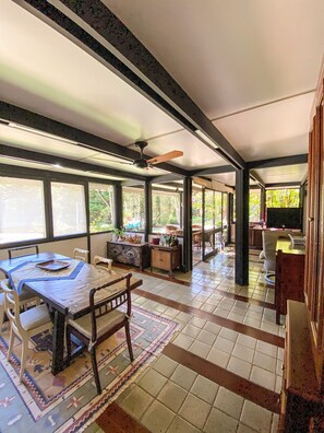 A spacious room with a dining area, a television, and a view of greenery outside. - Chácara Espetacular em Ibiúna (Ibiuna)