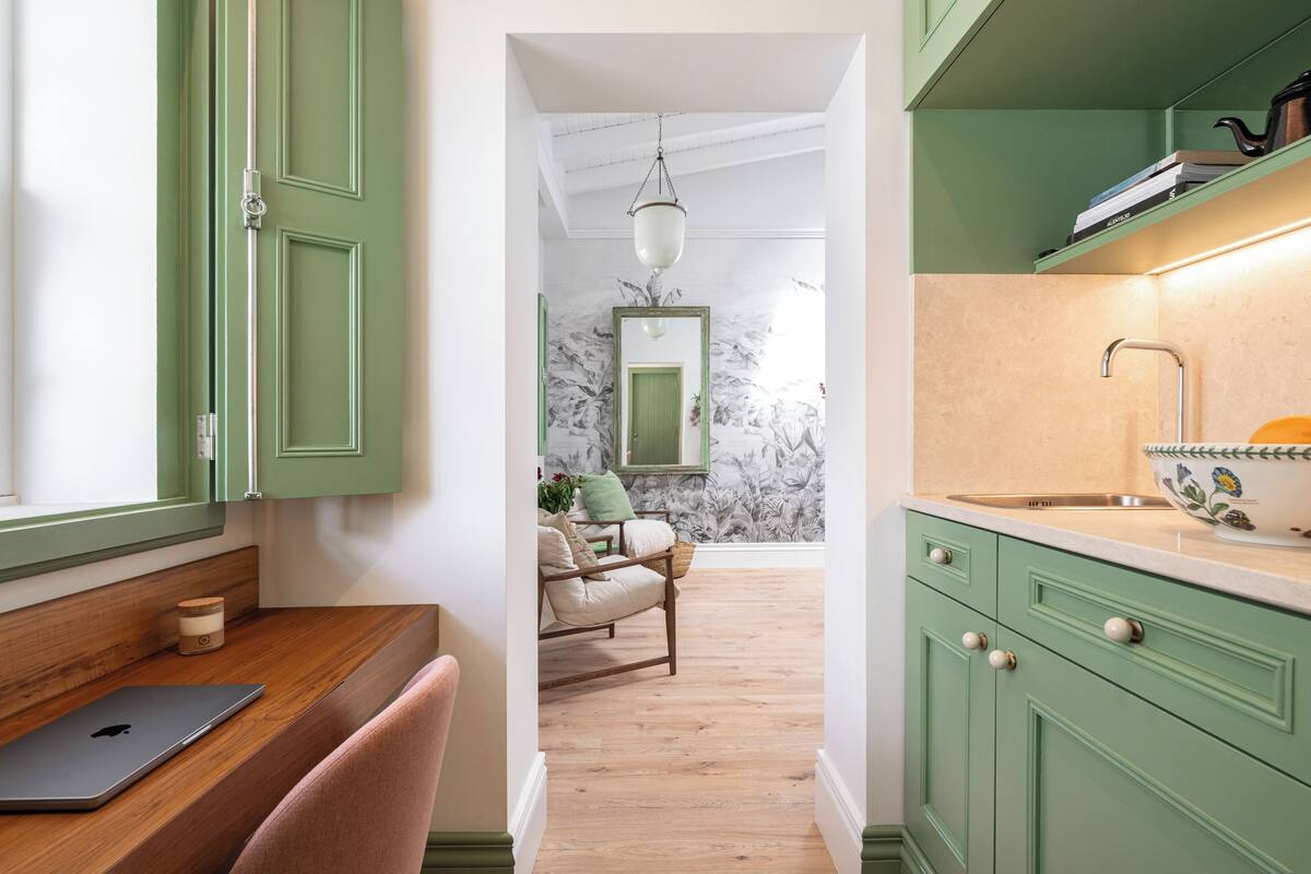 A kitchen with green cabinets, a wooden countertop, and a sink.