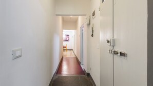 A narrow hallway with a red carpet, white walls, and a door on the right. - Osteria del Guanto by Mmega (Florence)