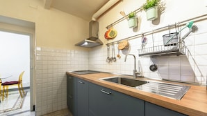 A kitchen with a wooden countertop, a stainless steel sink, and a hanging rack with kitchen utensils. - Osteria del Guanto by Mmega (Florence)