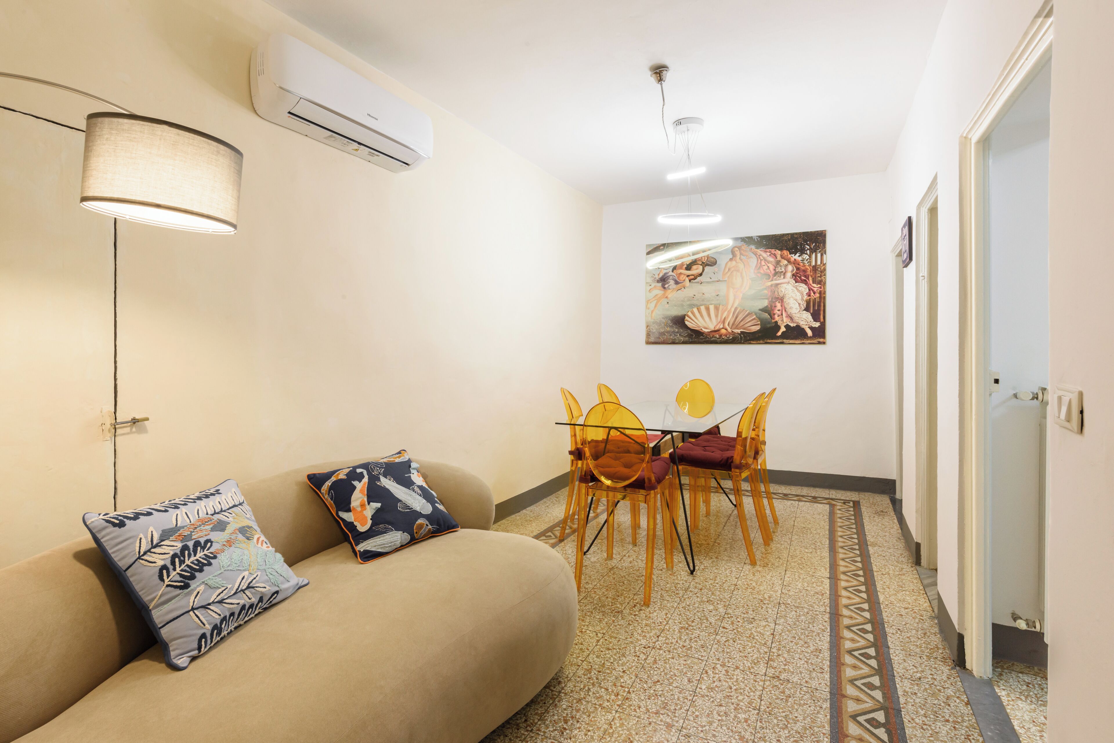 A modern living room with a sofa, a table with chairs, and a painting on the wall.