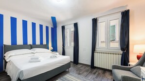 A modern bedroom with a bed, a chair, and a window with curtains. - Osteria del Guanto by Mmega (Florence)