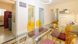 A modern dining area with a glass table and chairs, a sign indicating free Wi-Fi, and a cozy seating area with a lamp. - Osteria del Guanto by Mmega (Florence)