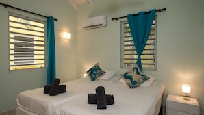 Een hotelkamer met twee bedden, een nachtkastje met een lamp en een airconditioner aan de muur.
