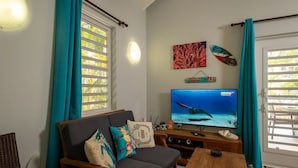 Een woonkamer met een bank, een televisie waarop een onderwaterlandschap staat en een houten salontafel.