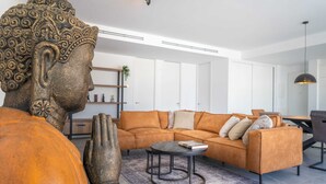 Un salon moderne avec une grande statue, un canapé, une table basse et un coin repas.